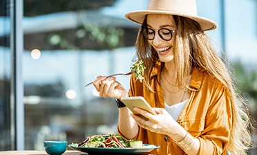 Smiling woman looking at her phone while eating lunch