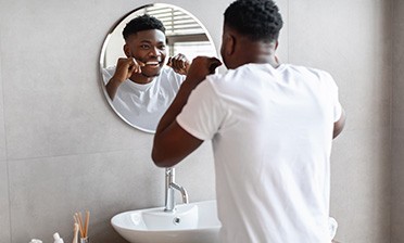 Smiling man flossing in bathroom