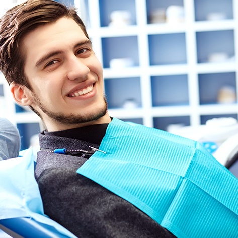 Male dental patient sitting in chair and smiling