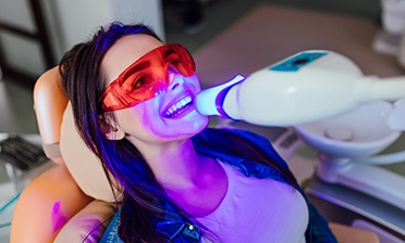 A smiling woman receiving in-office teeth whitening treatment