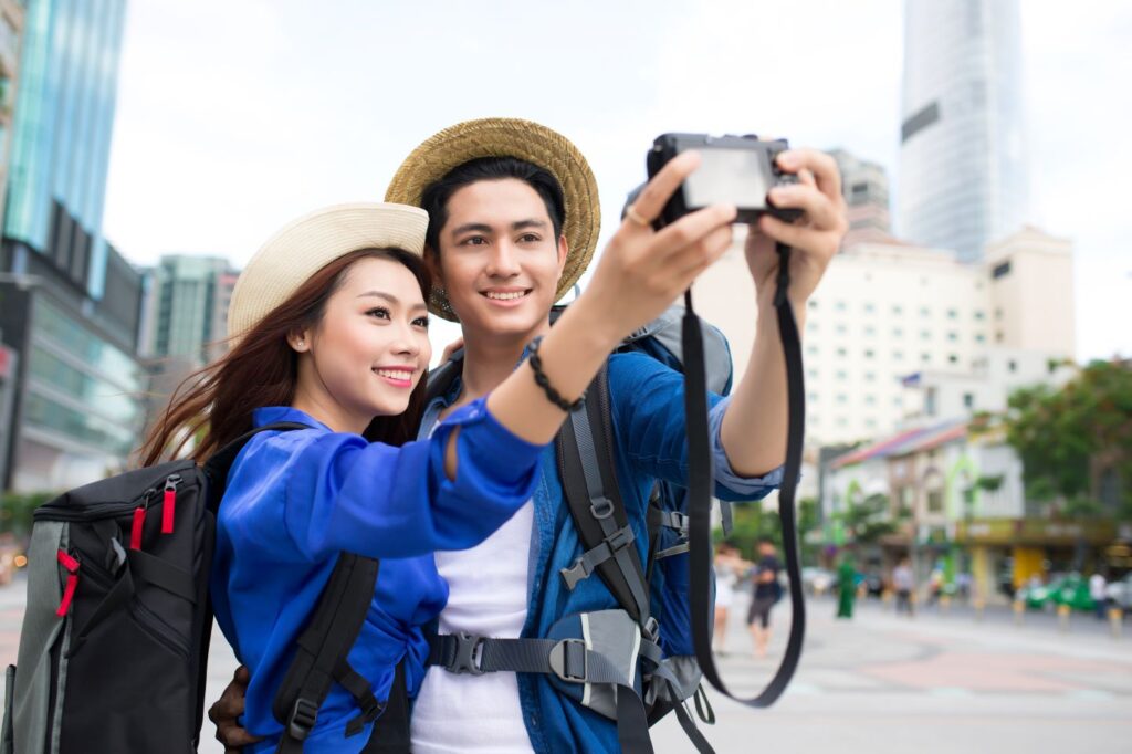 A man and a woman taking a photo together by a building.
